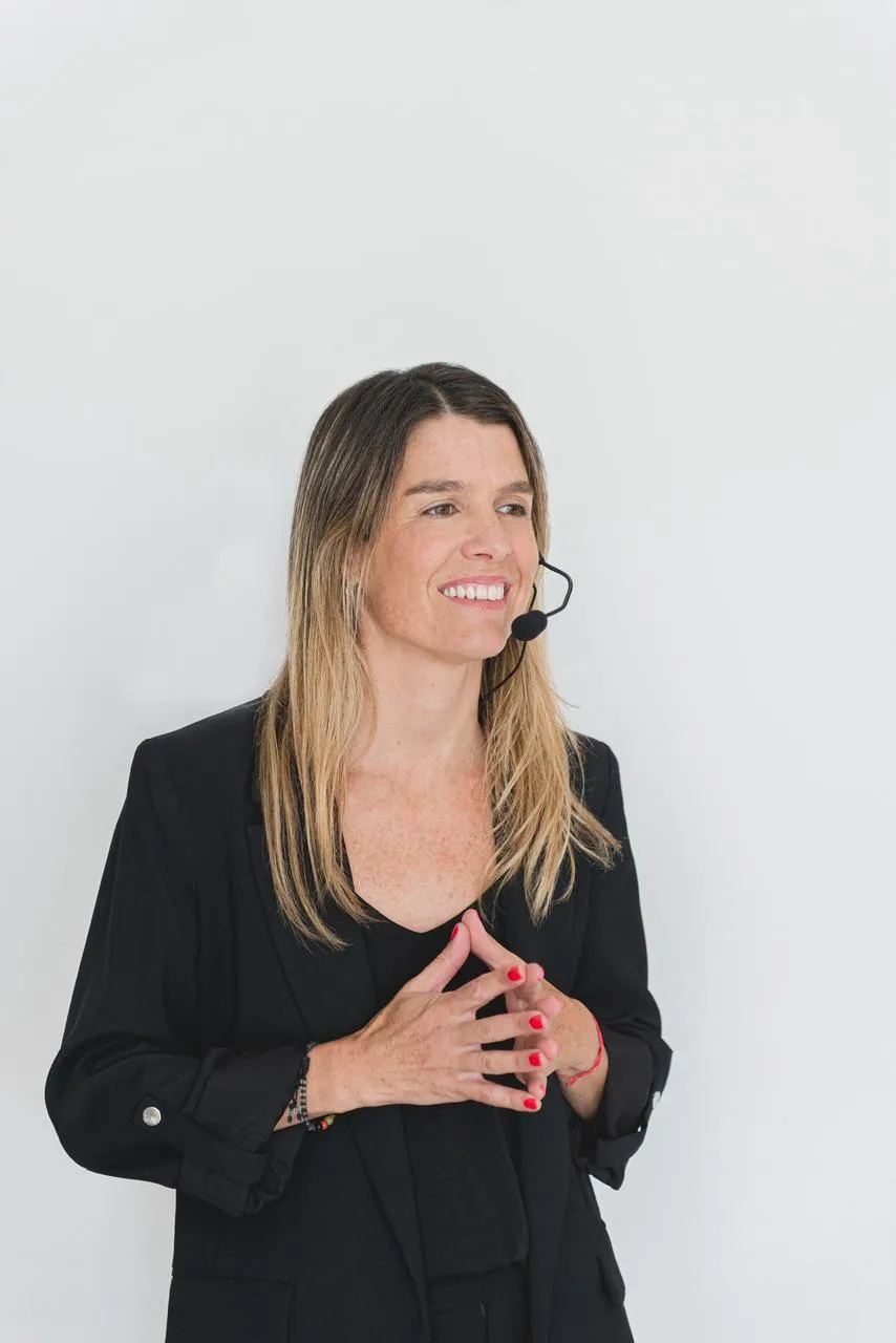 Natalia Goñi dando una charla con micrófono de vincha, gesticulando con las manos