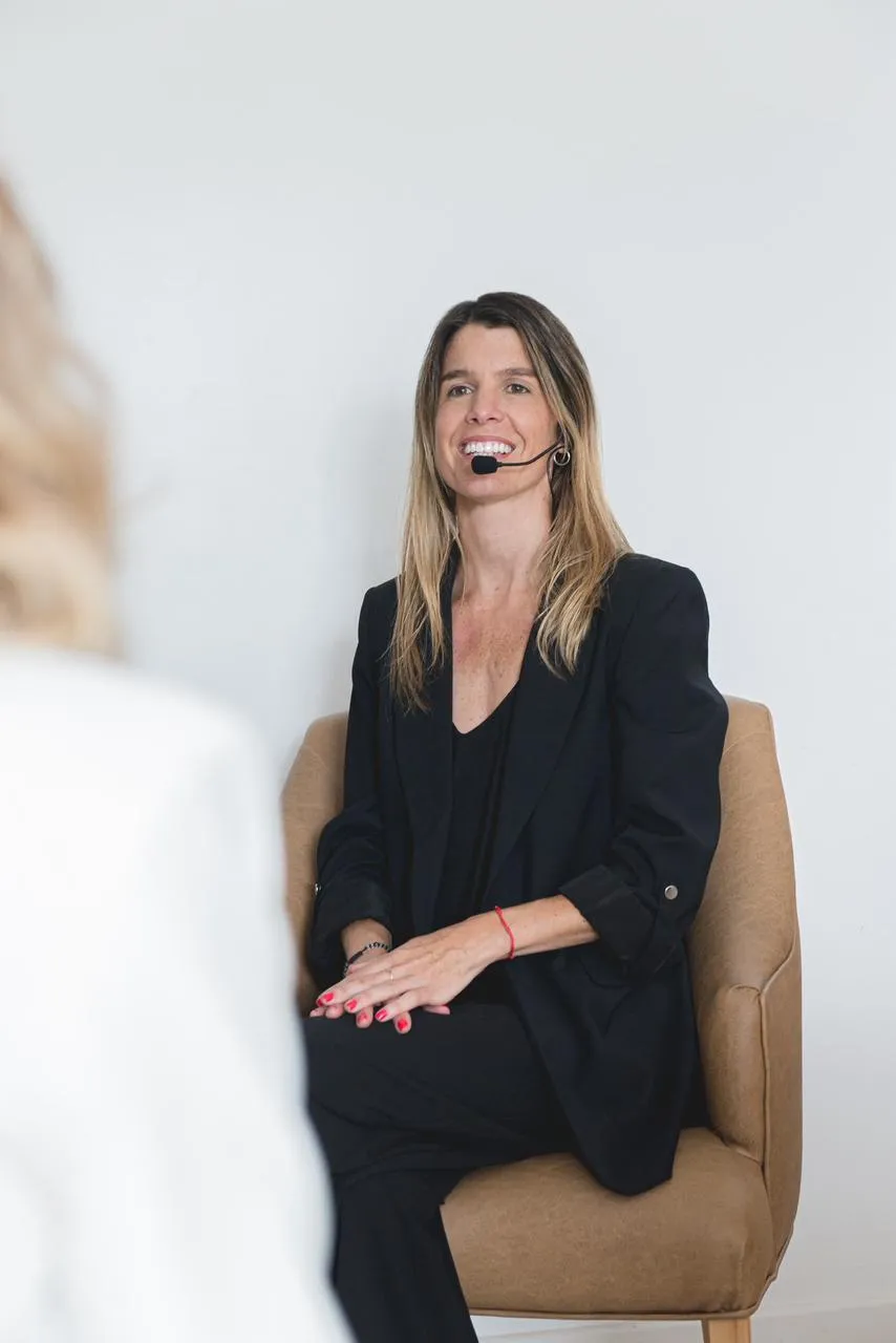 Natalia Goñi con micrófono de vincha, conversando con una participante durante un encuentro
