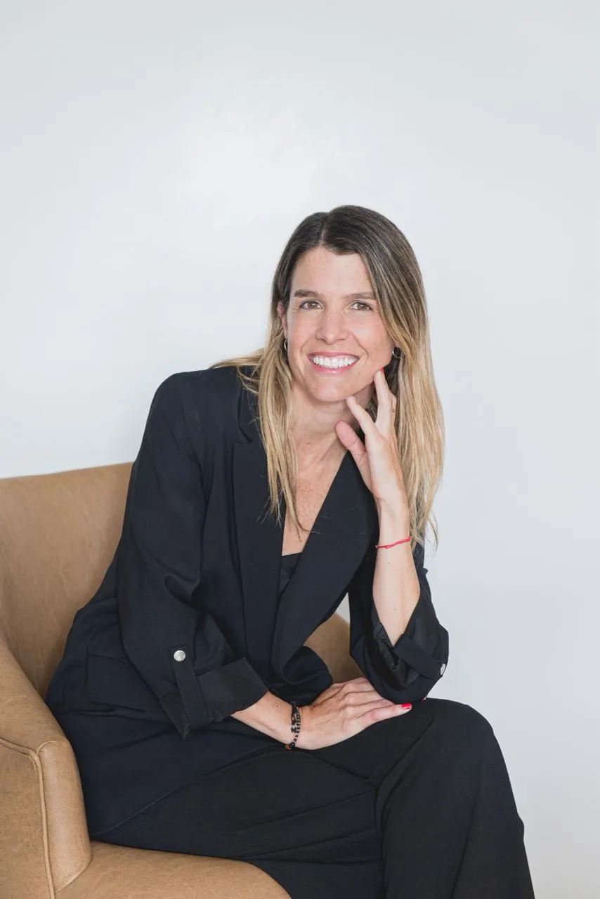 Natalia Goñi sentada en un sillón, sonriendo con la mano apoyada en el mentón