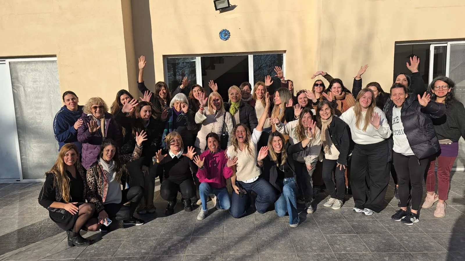 Grupo de mujeres del programa Desde Adentro saludando a cámara en el patio de una casa
